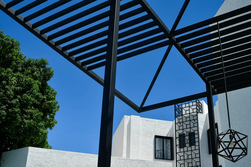 White facade with black pergola under the blue Cancún sky