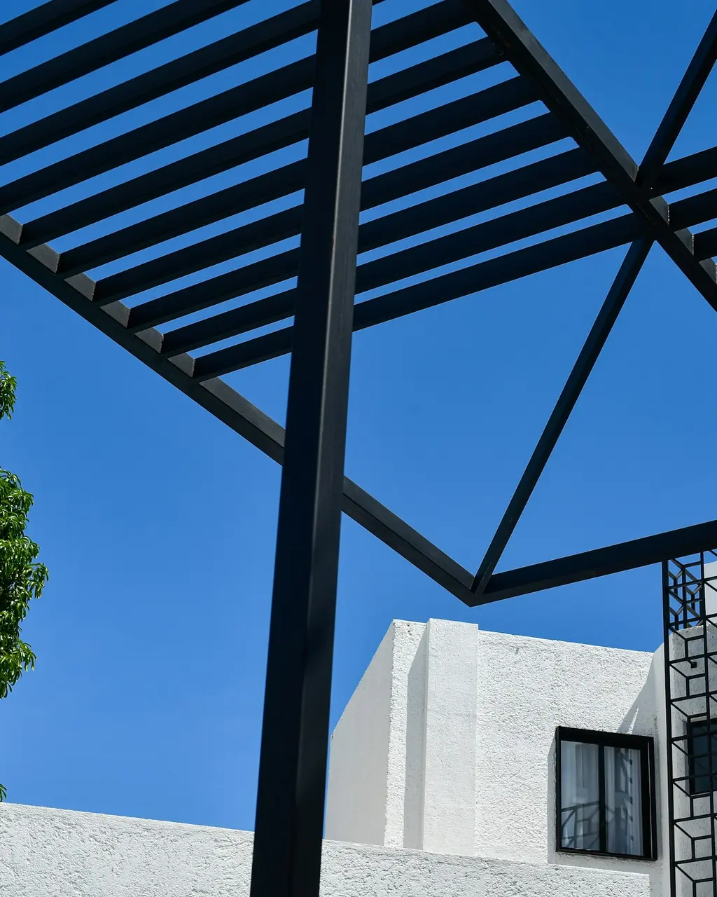 White facade with black pergola under the blue Cancún sky