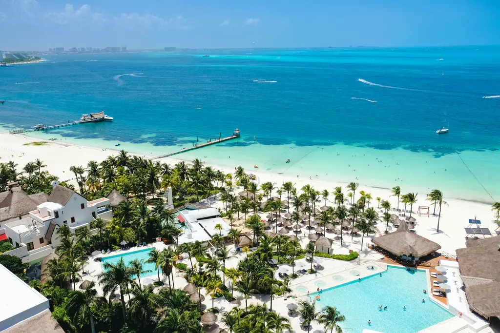 Aerial view of the Cancún coast with palm trees and turquoise sea