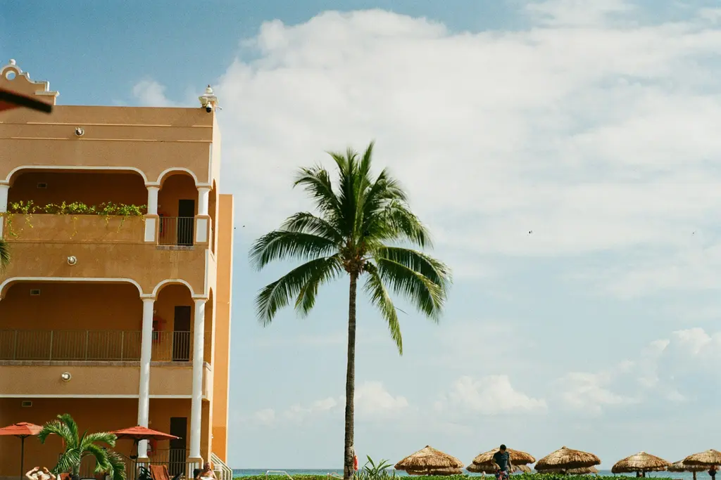 Mexican-style building with balconies and a palm tree by the sea in Playa del Carmen
