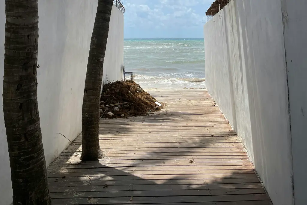 Walkway between white walls leading to the beach in Playa del Carmen