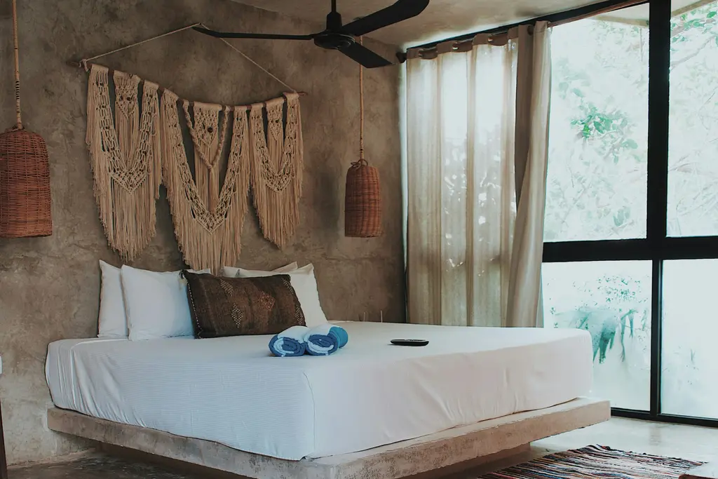Bedroom with white bed, large window and ceiling fan in Tulum