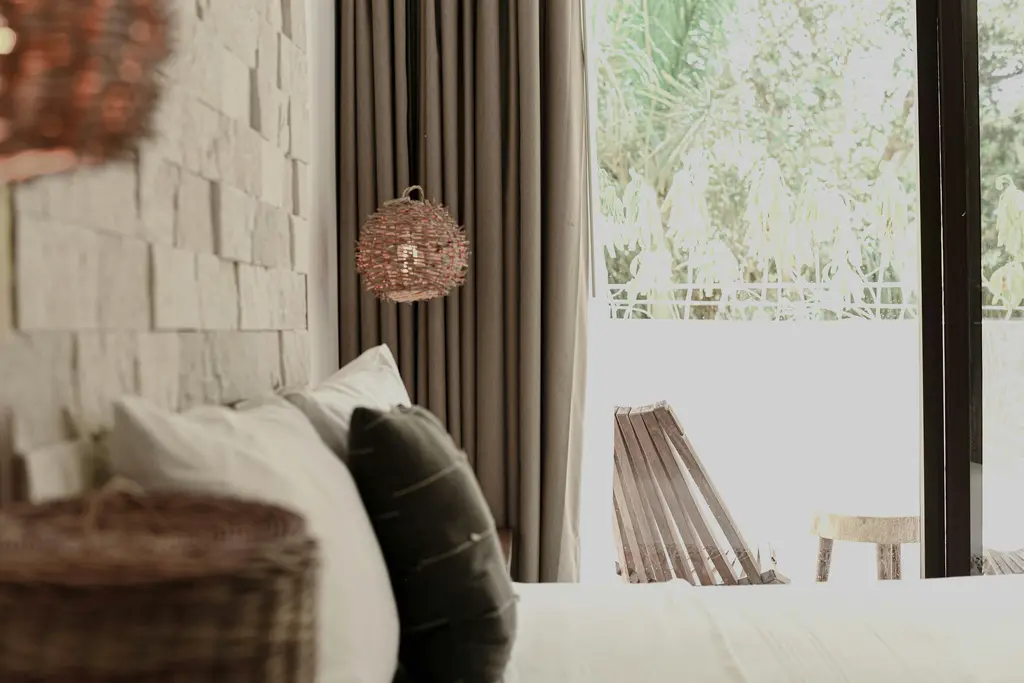 Bedroom with stone wall and white bed in Tulum